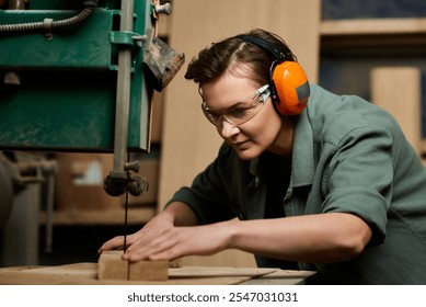 A focused female carpenter expertly works on wood at her workshop, surrounded by tools and materials. - Powered by Shutterstock