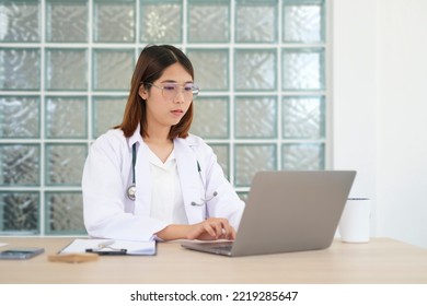 Focused Female Doctor In White Uniform Browsing Medical History On Laptop Computer.