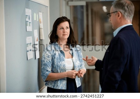 Focused female executive explaining complex data and business strategy on a bulletin board. Professional team collaboration and focused leadership.
