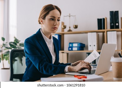 Focused Female Lawyer Working On Laptop At Workplace In Office
