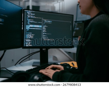 Focused Female IT Programmer working in software developing office, Writing code using desktop computer review and analysis data on monitor screen developing a new software app development project.
