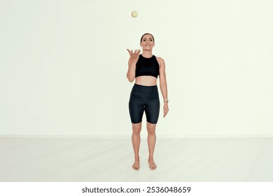 A focused female trainer tosses a tennis ball in the air, showcasing coordination and balance. Ideal for concepts related to fitness, control, and athletic training.. - Powered by Shutterstock