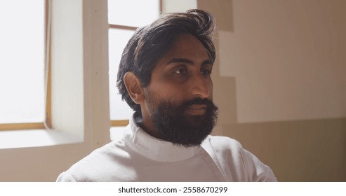 Focused fencer in white uniform preparing for match in bright room. Fencing, preparation, athlete, sports, competition, concentration - Powered by Shutterstock