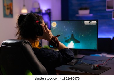 Focused Gamer puts professional headphones and playing space shooter videogames use modern equipment for digital tournament. Pro player sitting on gaming chair streaming video games using RGB keyword - Powered by Shutterstock