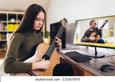 Focused girl playing acoustic guitar and watching online course on laptop while practicing at home. Online training, online classes. - Powered by Shutterstock