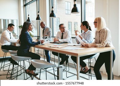 Focused group of diverse businesspeople discussing paperwork together during a meeting around a table in a modern office