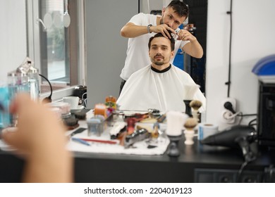 Focused hair stylist taking care of gentleman haircut at salon - Shutterstock ID 2204019123
