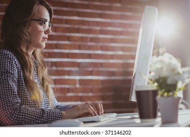 Focused Hipster Businesswoman Watching Computer At Her Desk In Office