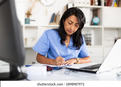 Focused Hispanic Female Doctor Working With Laptop In Clinic Office. Modern Medicine And Healthcare Concept