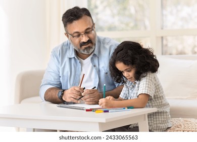 Focused Indian grandfather and cute granddaughter kid drawing creative colorful doodles in paper album together, developing art skills, creativity, hobby, doing school homework - Powered by Shutterstock