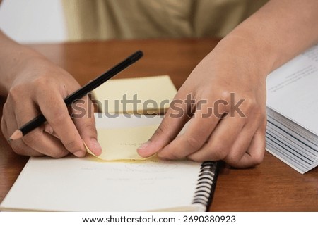 A focused individual organizes notes using sticky notes in a home office setting.