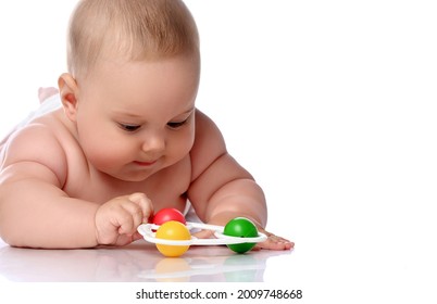 Focused Infant Child Baby Girl Kid In Diaper Is Lying On Her Stomach Playing With Rattle, Touching With Hand Isolated On A White Background