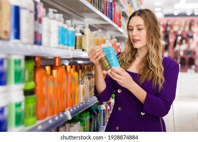 Focused Interested Glad Beautiful Girl Shopping In Cosmetics Store Looking For Hair Care Treatments