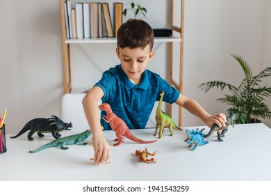 Focused Kid Playing With Dinosaurs At Home. Boy Learning Paleontology By Dino Toys At Leisure. Concept Of Clever Child And Early Education