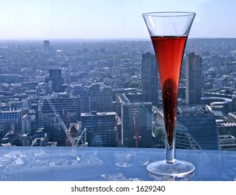 Focused Kir Royal cocktail with slightly blurry aerial view of London