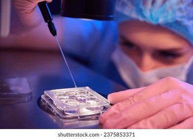 Focused lab scientist collecting in vitro cultured embryos for biopsy