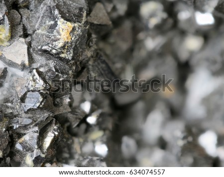 Focused left part of image showing mineral ore dark grey texture of a rocky lead zinc pattern crystalline structure