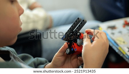 Focused little boy assembles toy of construction set details in airplane salon. Toddler child builds machine of plastic parts sitting on passenger chair