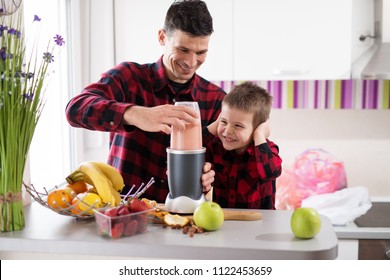 Focused loving father is using the blender to make smoothie while his son is holding ears while smiling in a bright kitchen. - Powered by Shutterstock