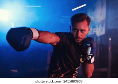 Focused male boxer practices punches alone in a gym with dramatic red and blue lighting, creating a vivid, energetic atmosphere - Powered by Shutterstock