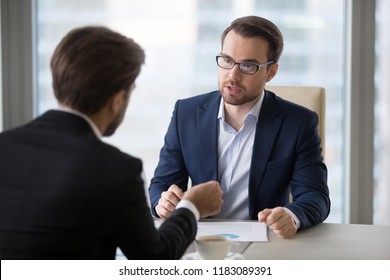 Focused Male Business Partners Negotiate At Office Table Discussing Statistics, Male Managers Talk About Sales And Contract Terms, Businessmen Consider Deal Closing, Speak About Success Strategies