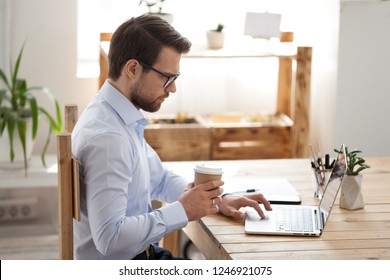 Focused male business worker surfing web drinking coffee in loft office, concentrated entrepreneur enjoy espresso using computer at workplace, employee routine morning working or browsing internet - Powered by Shutterstock