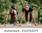 Focused male and female athletes poised at the start line on a running track in a green park, preparing for a sprint.