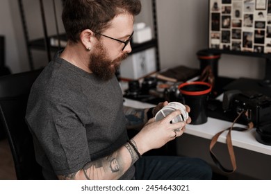 A focused male photographer sits in a studio, meticulously examining strips of film negatives for perfect shots. - Powered by Shutterstock