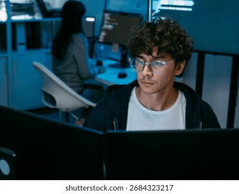 Focused Male IT Programmer working in software developing office, Writing code using desktop computer review and analysis data on monitor screen developing a new software app development project.
