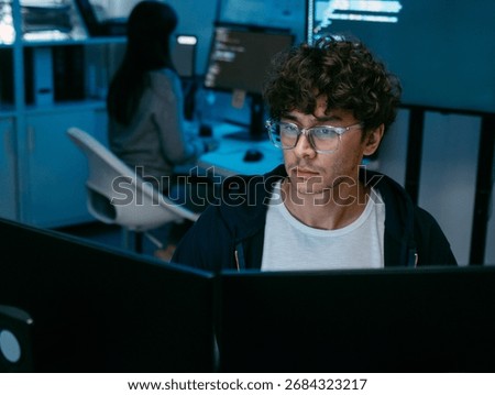 Focused Male IT Programmer working in software developing office, Writing code using desktop computer review and analysis data on monitor screen developing a new software app development project.