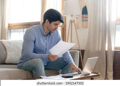 Focused Man Checking Financial Documents, Paying Bills Or Taxes Online, Using Laptop, Planning Managing Budget, Sitting On Couch, Accounting Expenses, Calculating Money, Rent Or Mortgage Payment