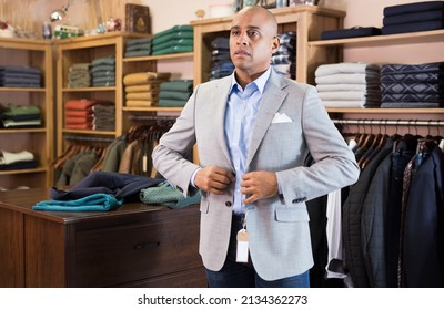 Focused Man Deciding On Suit Jacket While Shopping At Apparel Shop