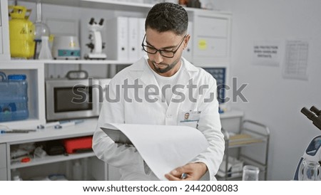 Focused man in labcoat analyzing documents in a modern laboratory setting