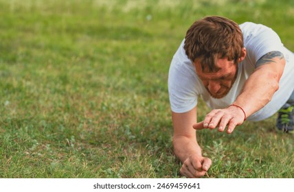 A focused man performs push-ups on a grassy field during early morning hours.