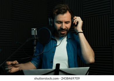 Focused man records audio while reading a script in a professional soundproof studio