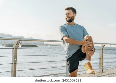 A focused man stretches his leg on a sunlit boardwalk by the river, gazing into the distance, contemplating his workout.

 - Powered by Shutterstock