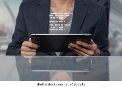 A focused man in a suit analyzes binary code displayed on a tablet, showcasing technology and professionalism in a modern workspace. The reflective surface enhances the visual appeal.