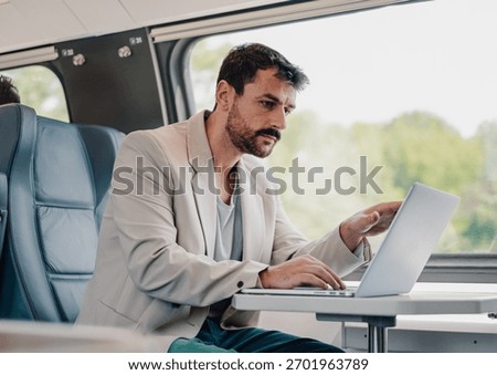 Focused man in train using laptop for work, remote business, and digital nomad lifestyle, combining travel with productivity