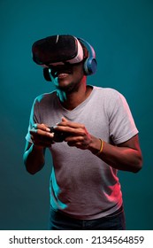 Focused man using controller and vr glasses to play futuristic game online. Gamer playing virtual reality simulation on interactive headset with joystick, advertising 3d modern technology.