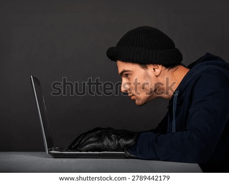 Focused man using a laptop in a dark environment, concept of hacking, cybercrime and digital security threats.