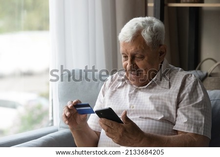 Focused man using mobile phone and making online payment by credit card. Customer shopping from home, paying for purchase on Internet stores, using banking or ecommerce app for transactions