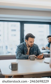 Focused man using smart phone in a cafe with people in background.