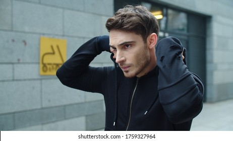 Focused Man Walking Street In Slow Motion. Portrait Of Sexy Man In Sportswear On Urban Street. Closeup Stylish Guy In Black Sweatshirt On Urban Background.