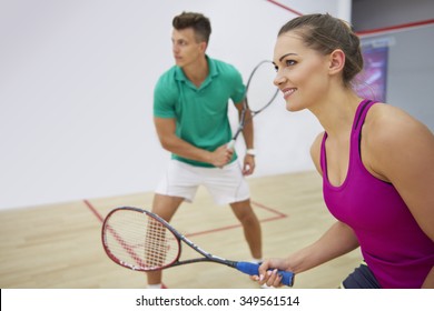 Focused man and woman playing squash together