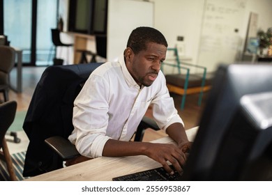 Focused man working on dual monitors in office