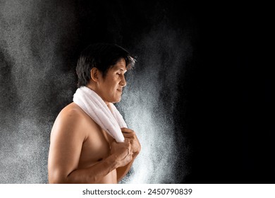 Focused man wrapping a towel around his neck, with sweat particles visible in the air, capturing the intensity of his training session - Powered by Shutterstock