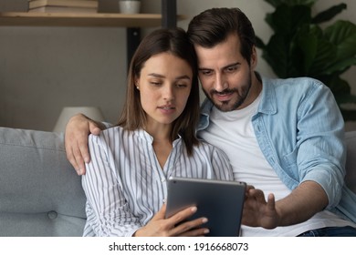 Focused Married Couple Read Insurance Policy Loan Contract Text From Bank Website On Tablet Screen Planning To Make Treaty. Serious Young Spouses Hold Digital Pad Device Buy Goods Order Service Online