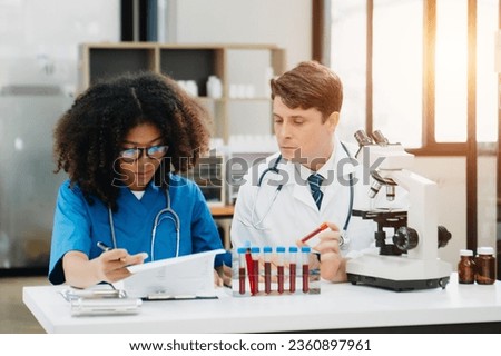 Focused mature male doctor and African female nurse look at tablet and laptop screen discuss anamnesis together. Concentrated diverse medical professionals in hospital. ストックフォト © 