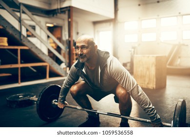 Focused mature man in sportswear preparing to lift weights while working out alone in a gym - Shutterstock ID 1059536558