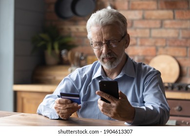 Focused Mature Retired Man Holding Bank Credit Card, Entering Payment Information In Mobile Shopping Application, Purchasing Goods Or Services In Online Store, Old People And Modern Tech Concept.